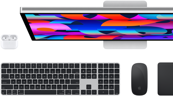 En Studio Display-skjerm vist fra oversiden, Magic Keyboard i svart, Magic Mouse i svart, Magic Trackpad i svart og AirPods-etui i hvit